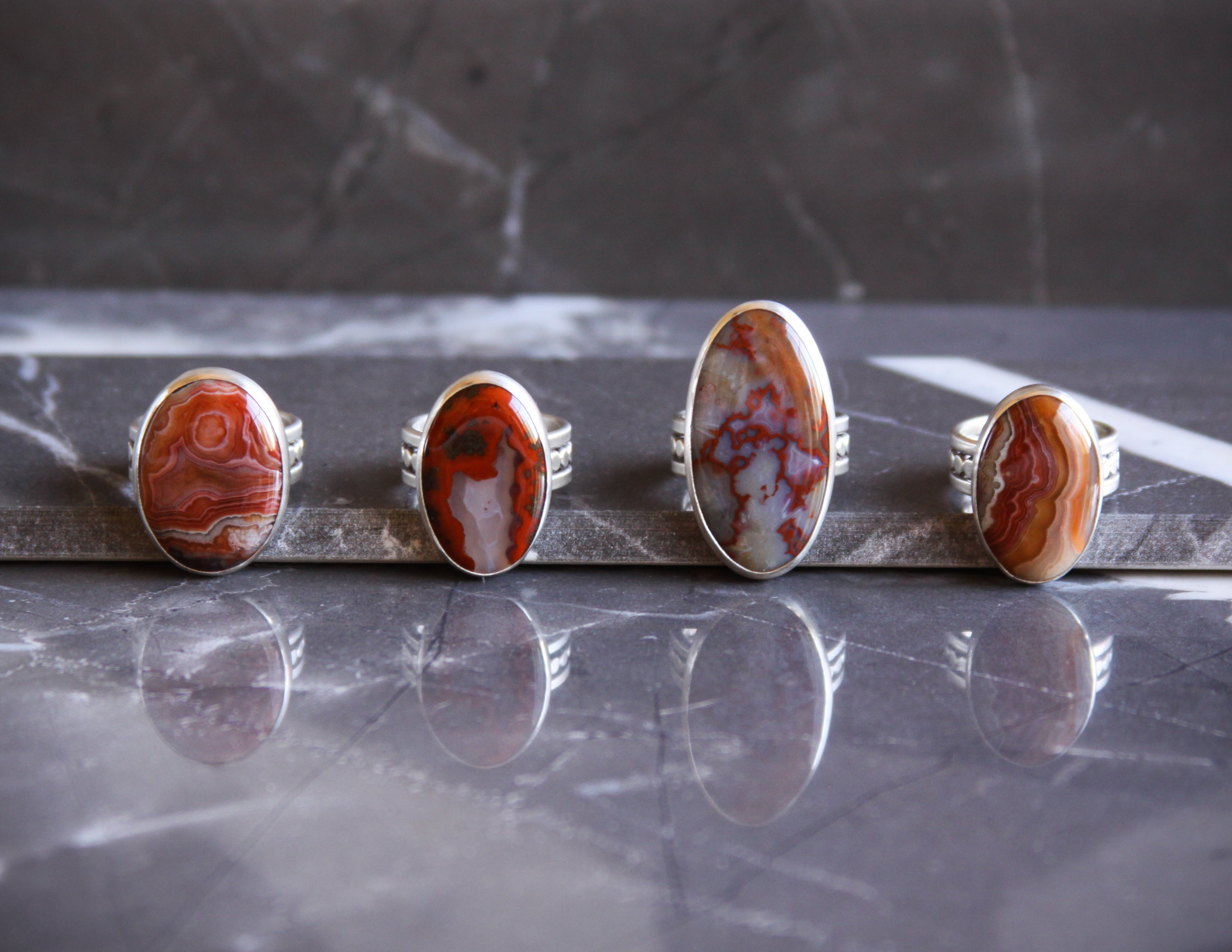 Collection of dark red and white hued agate and jasper silver cocktail rings with unique wide bands